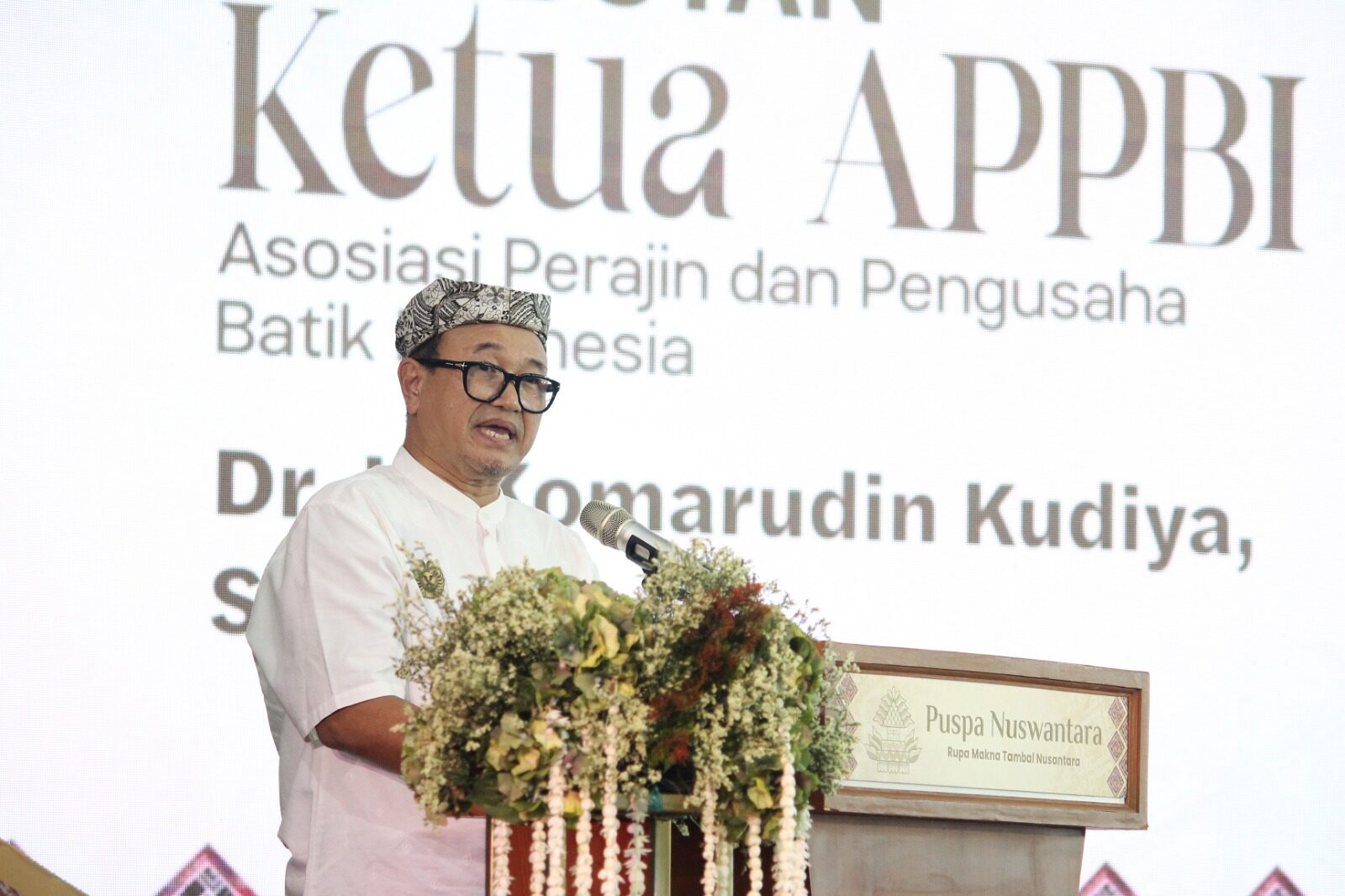 Sambutan Ketua Umum APPBI Komarudin KudiyaKetua Umum Asosiasi Perajin dan Pengusaha Batik Indonesia (APPBI) Komarudin Kudiya menyampaikan sambutan pada pembukaan Puspa Nuswantara 2026. Ia menyoroti pentingnya perlindungan terhadap batik asli di tengah maraknya kain bermotif batik yang beredar di pasaran. (Foto: Dok.  APPBI)